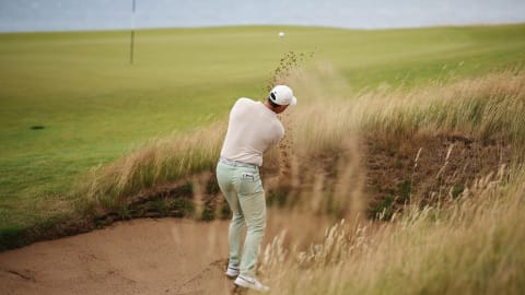 Rory McIlroy of Northern Ireland looks to get up and down from a greenside bunker