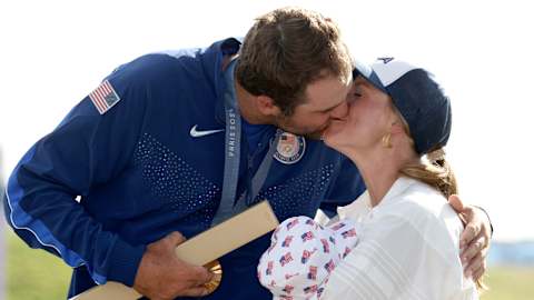 Scottie Scheffler celebrates victory with his wife, Meredith, as she carries their son, Bennett