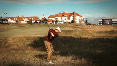 Rory McIlroy of Northern Ireland hits out of the rough in front of the clubhouse