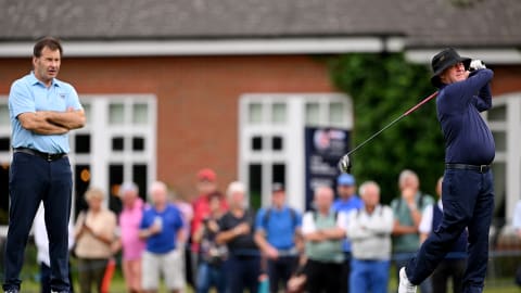 Host Sir Nick Faldo watches on as JP McManus hits a tee shot