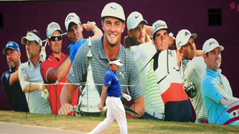 Ian Poulter walks past a promotional poster