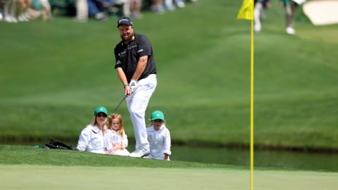 Shane Lowry chips onto the green while his family watches on