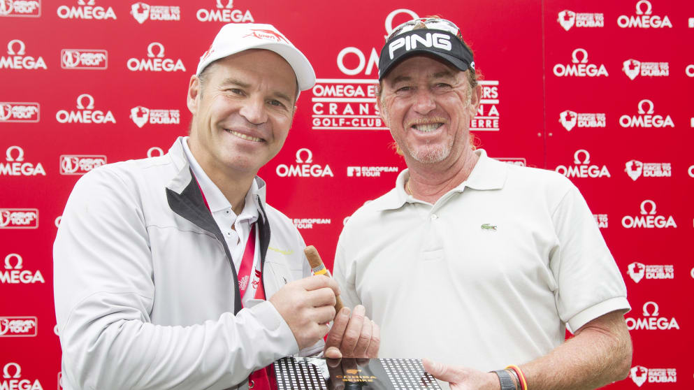 Miguel Angel Jiménez (right) receives a box of cohiba premium cigars from Marc Girardelli