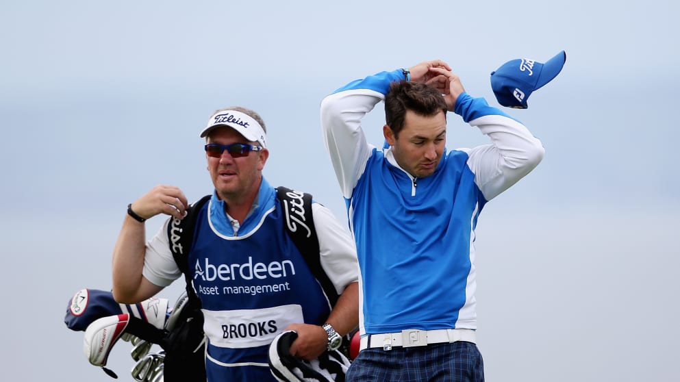 Wind blows the hat off the head of Daniel Brooks as he walks with his caddie on the ninth