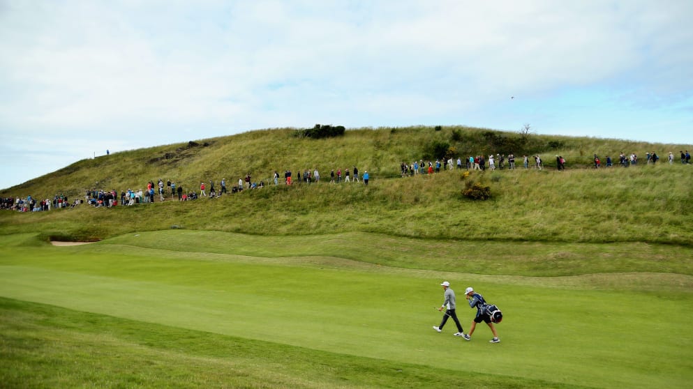 Rickie Fowler and caddie Joseph Skovron walk up the first hole