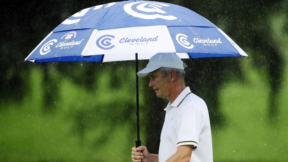 Jean Pierre Sallat shelters from the rain under an umbrella 