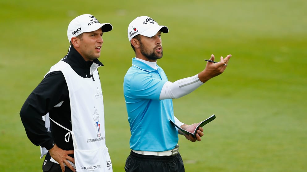 Andrey Pavlov of Russia (R) talks with his caddie on the sixteenth fairway 