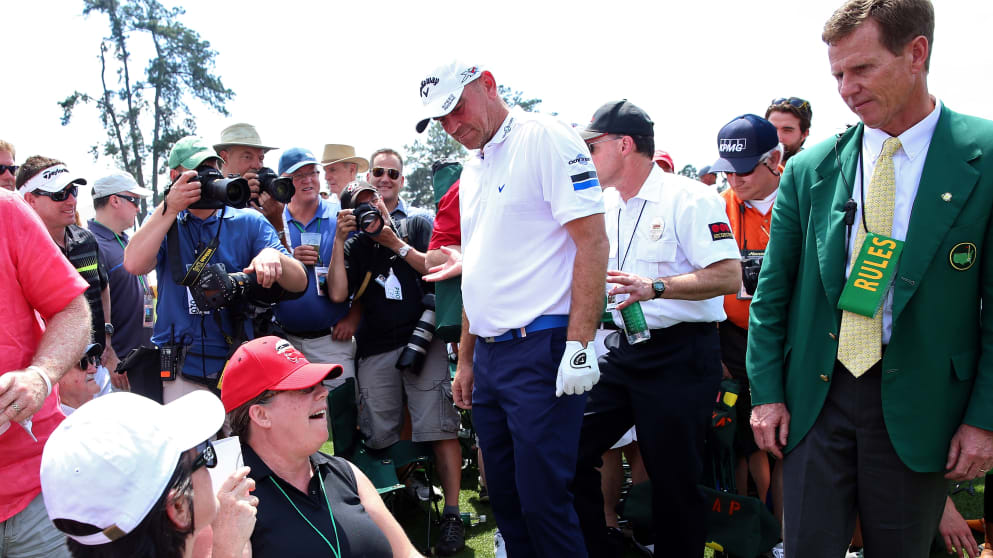 Thomas Bjorn and a rules official look down to Sharon Grenon after Bjorn's golf ball came to rest in her lap 