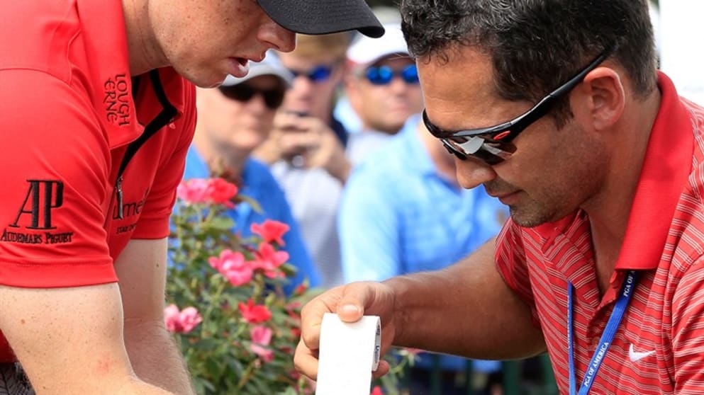 A member of the medical staff examines the right wrist of Rory McIlroy