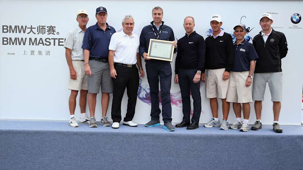 Marco Kaussler of BMW (centre) poses with a plaque after being made an honorary member of The European Tour Caddies' Association during a presentation at  the BMW Masters