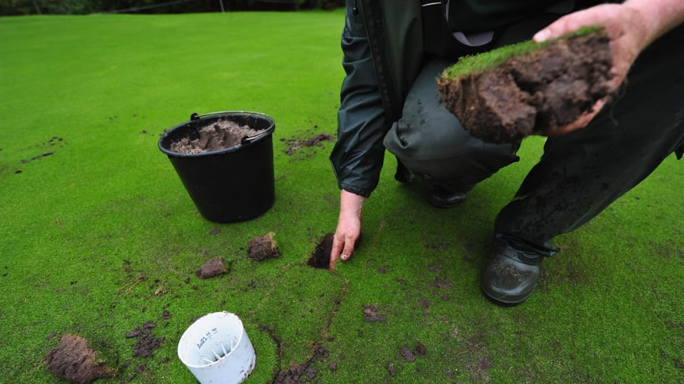 A greenkeeper repairs the damaged greens