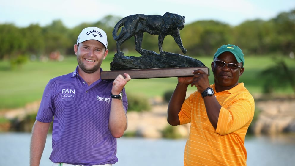 Branden Grace holds the Alfred Dunhill Championship trophy aloft with caddie Zack Rasego after his seven shot victory