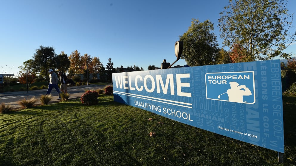 A golfer and caddie walk past the welcome sign prior to the second round of the European Tour qualifying school final stage at PGA Catalunya Resort