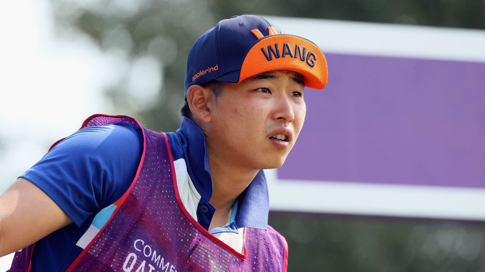 The caddie of Jeunghun Wang is pictured wearing an interesting hat with his player's name on