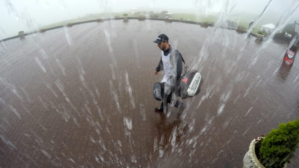 A caddie makes his way back to the club house as play is halted 