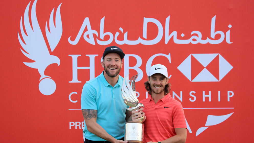 Tommy Fleetwood of England holds the Falcon Trophy with his caddie Ian Finnis